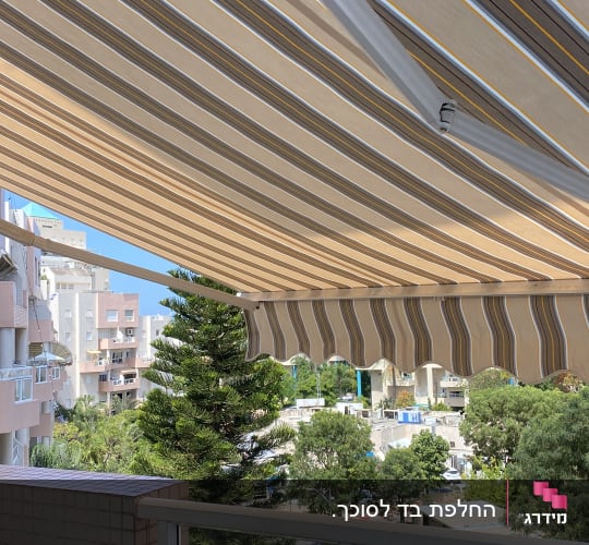 סוכך פסים בצבעים חום וצהוב על מרפסת